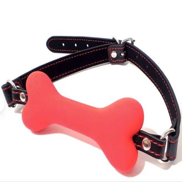 Red bone gag with black leather strap from Ideal Leather, featuring adjustable buckle and secure fit for BDSM restraint play.