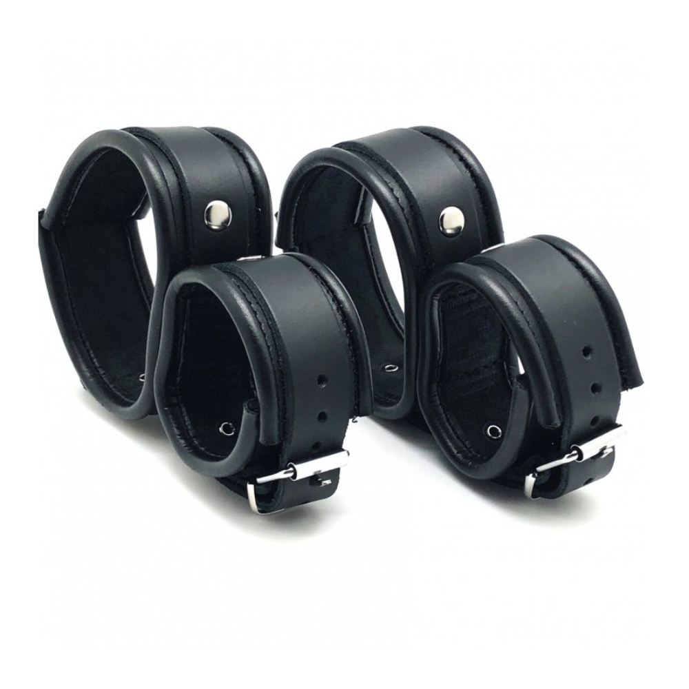 Black leather ankle and hand cuffs by Luvland with metal hardware, designed for bondage and restraint use.